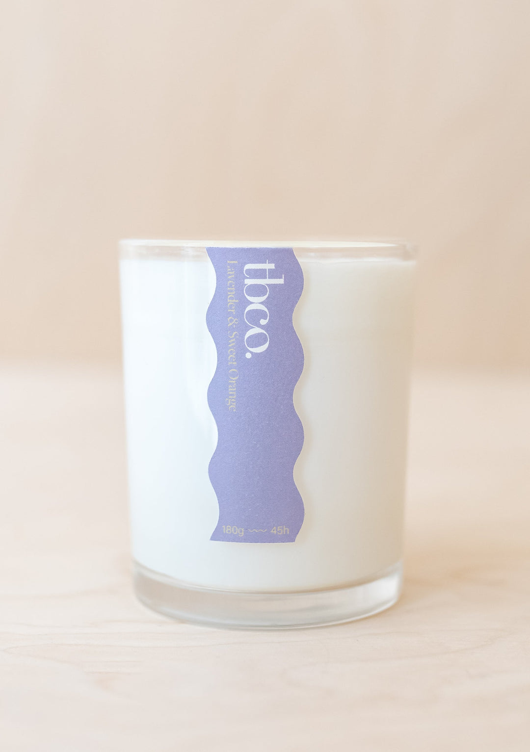 TBCo Lavender & Sweet Orange Candle in white recycled glass jar with lavender label against neutral background