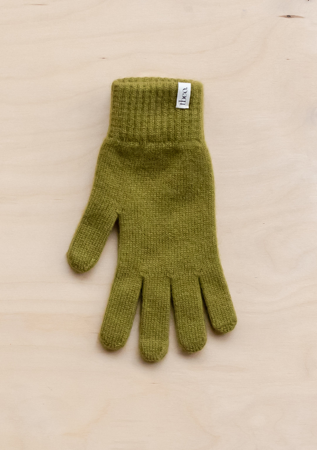 TBCo Cashmere & Merino Gloves in Olive, knitted wool winter glove with ribbed cuff and brand label, displayed on beige surface