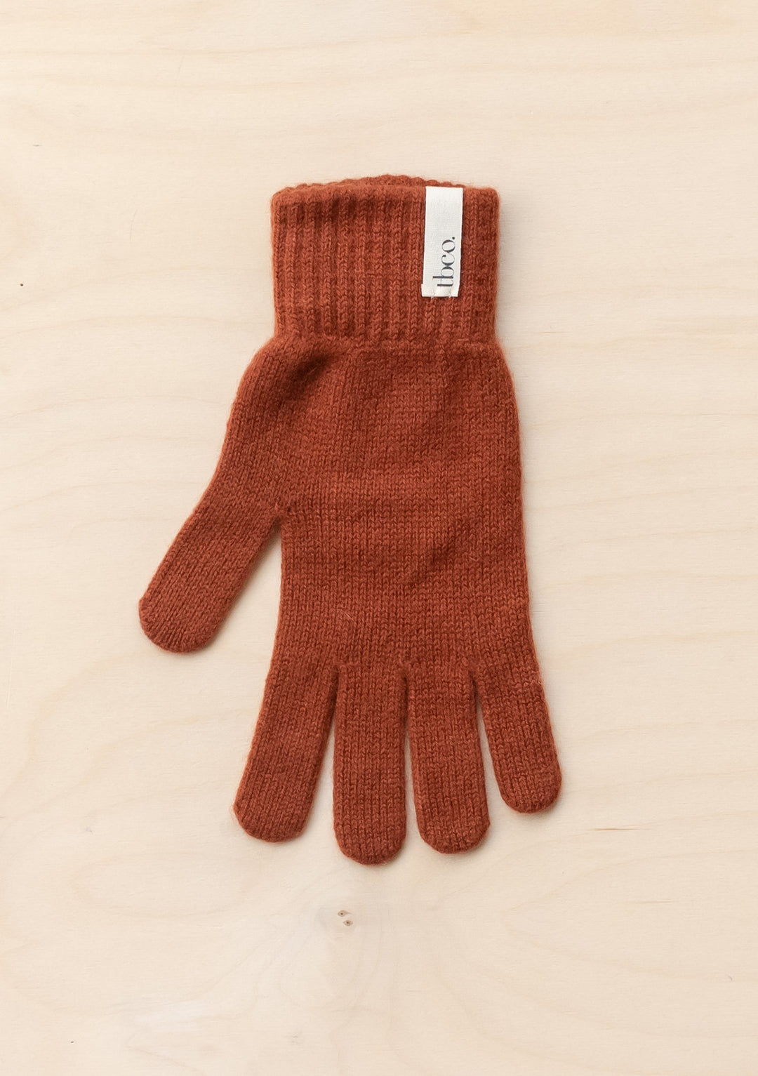 TBCo Cashmere & Merino Gloves in Rust, featuring ribbed knit texture and branded label, displayed on light background