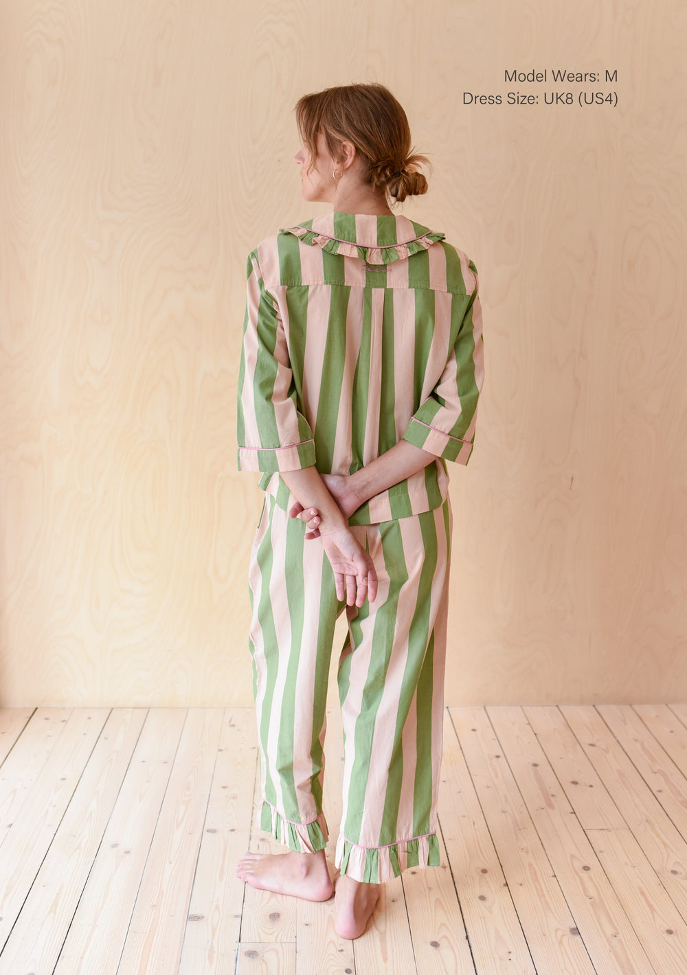 Back view of TBCo Cropped Cotton Pyjamas in Green Stripe with ruffled collar and cuffed sleeves on wooden floor background