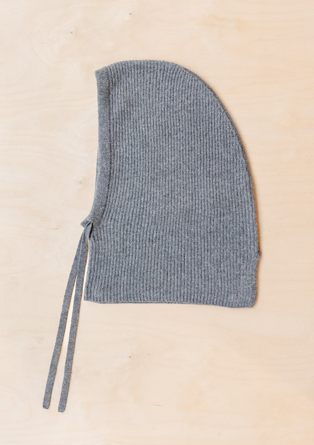 TBCo Merino Hood in Charcoal, ribbed knit wool winter hood with tie closures, photographed flat on beige surface