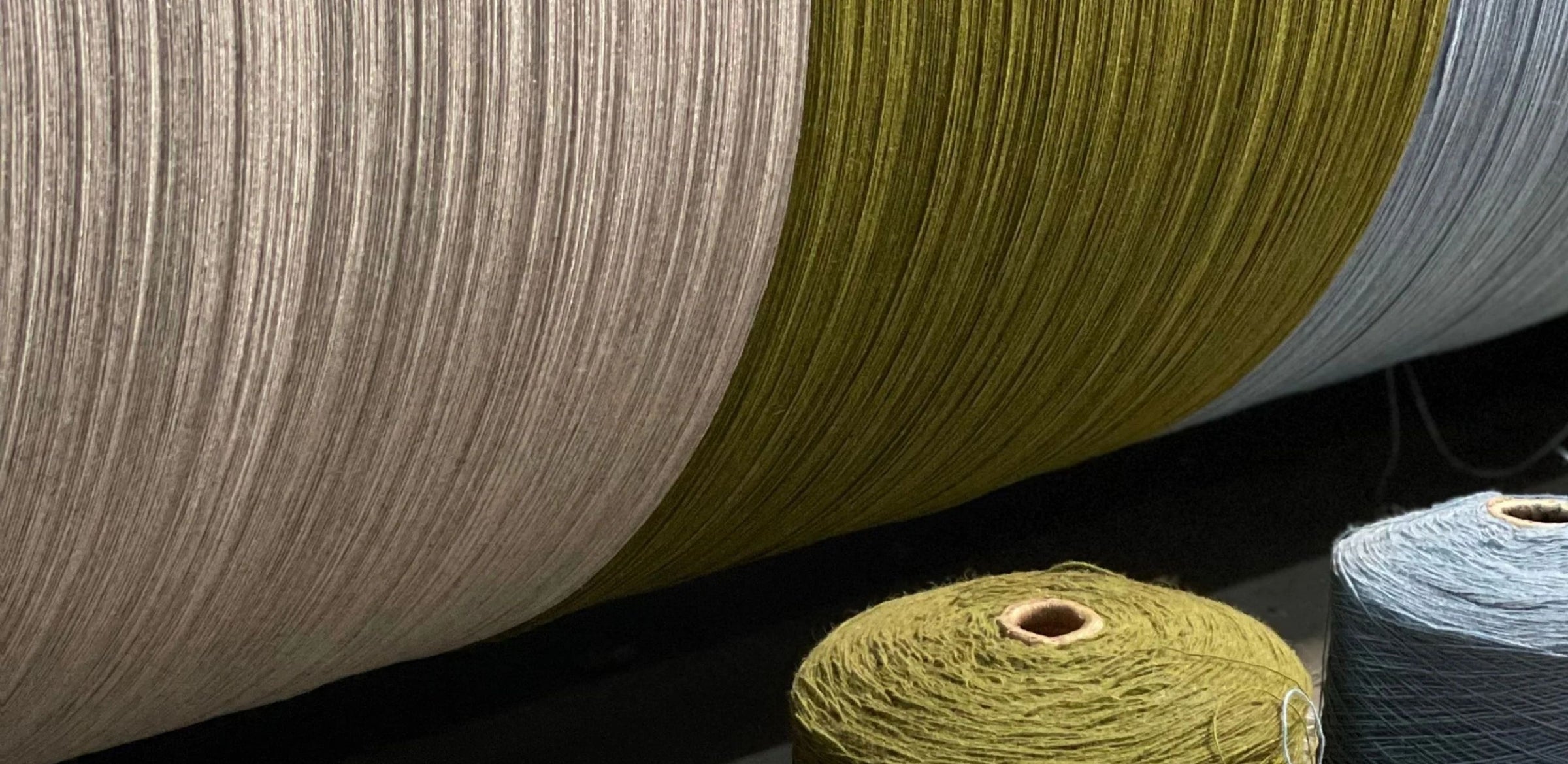 TBCo sustainable wool yarn in natural beige, olive green, and soft blue tones, carefully spun for ethical textile production. A close-up of high-quality fibres used in crafting premium wool blankets.