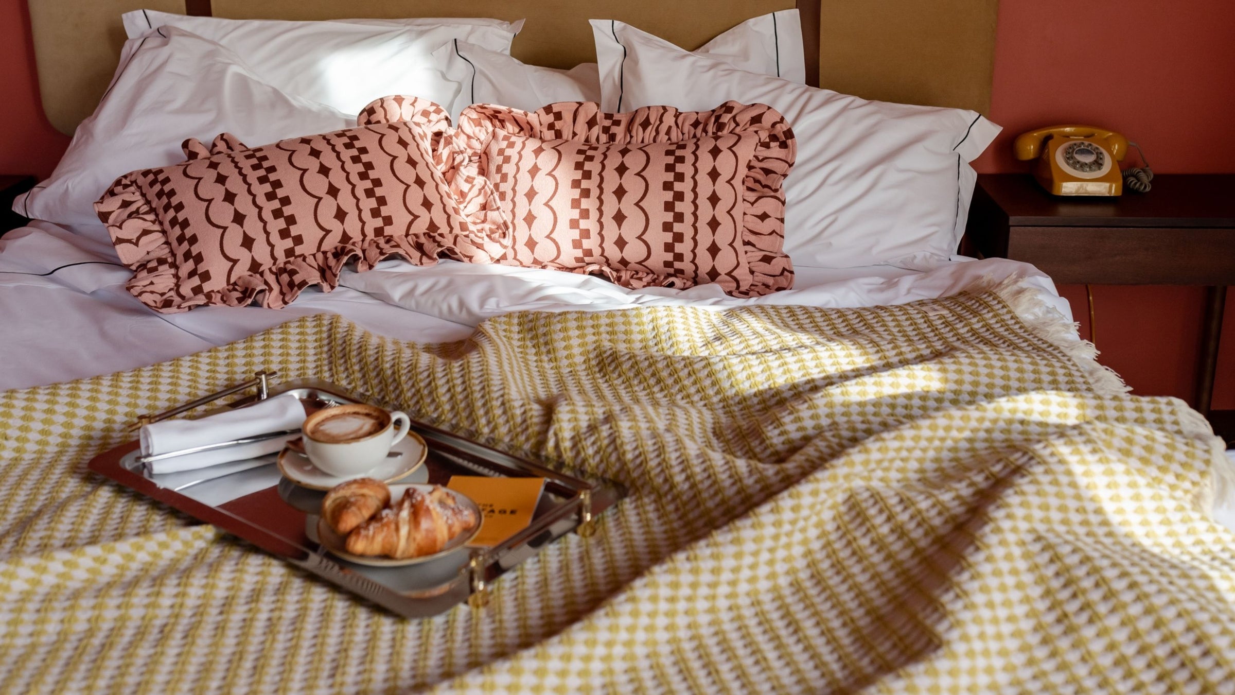 TBCo Cotton Olive Green Argyle Throw design draped over a cosy bed with textured TBCo Cotton Pink Ruffle Cushions. A perfect setting for relaxed mornings with coffee and pastries