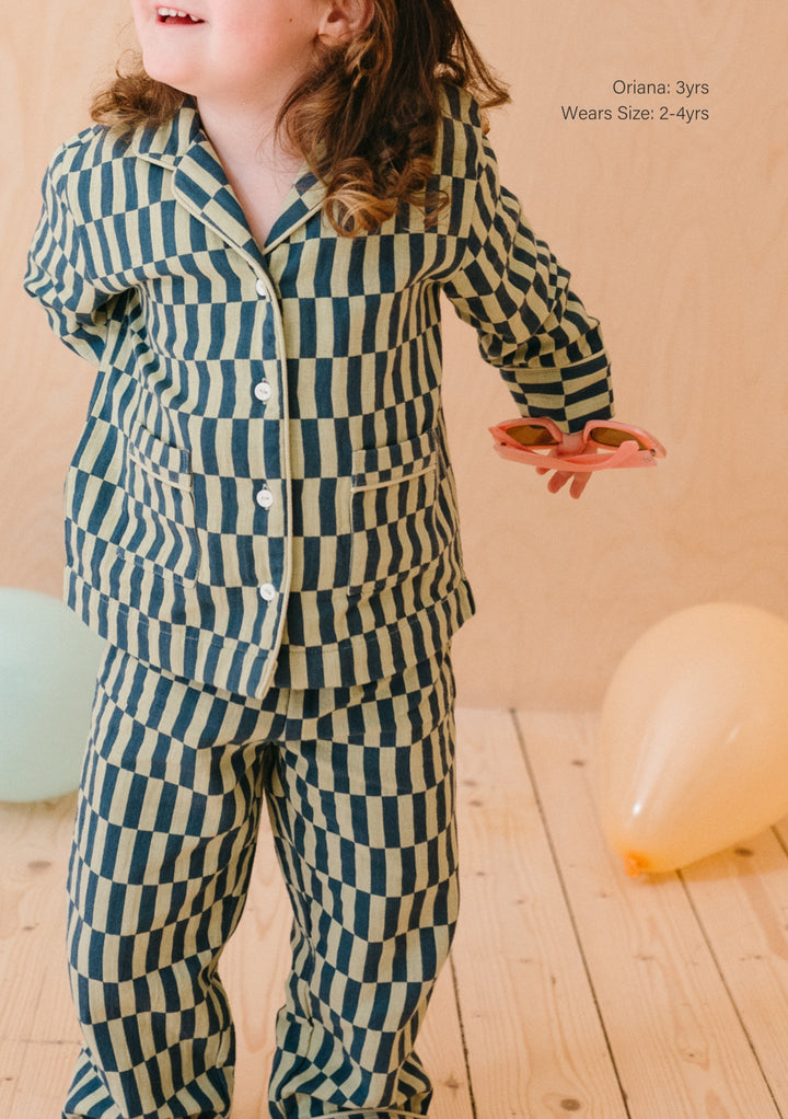 TBCo Cotton Kids Pyjamas featuring green and cream checkerboard pattern with collared top and matching bottoms, displayed on wooden floor