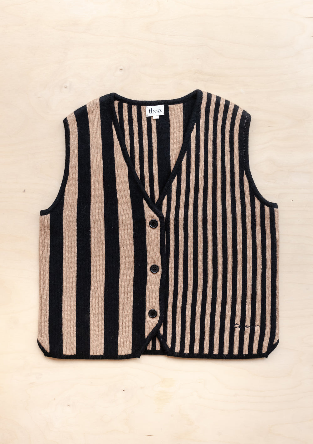 TBCo Merino Wool Vest in Latte Stripe featuring contrasting black and beige vertical stripes with V-neck design and button closure