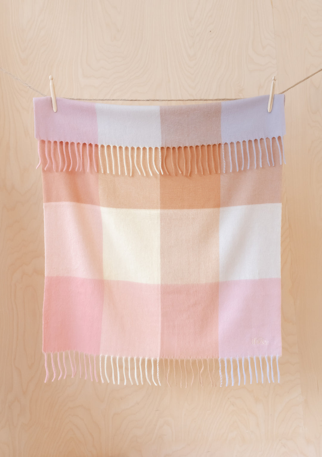 TBCo Lambswool Baby Blanket in Rose Block Check displaying soft pink, lilac and cream squares with delicate fringing, hung to dry