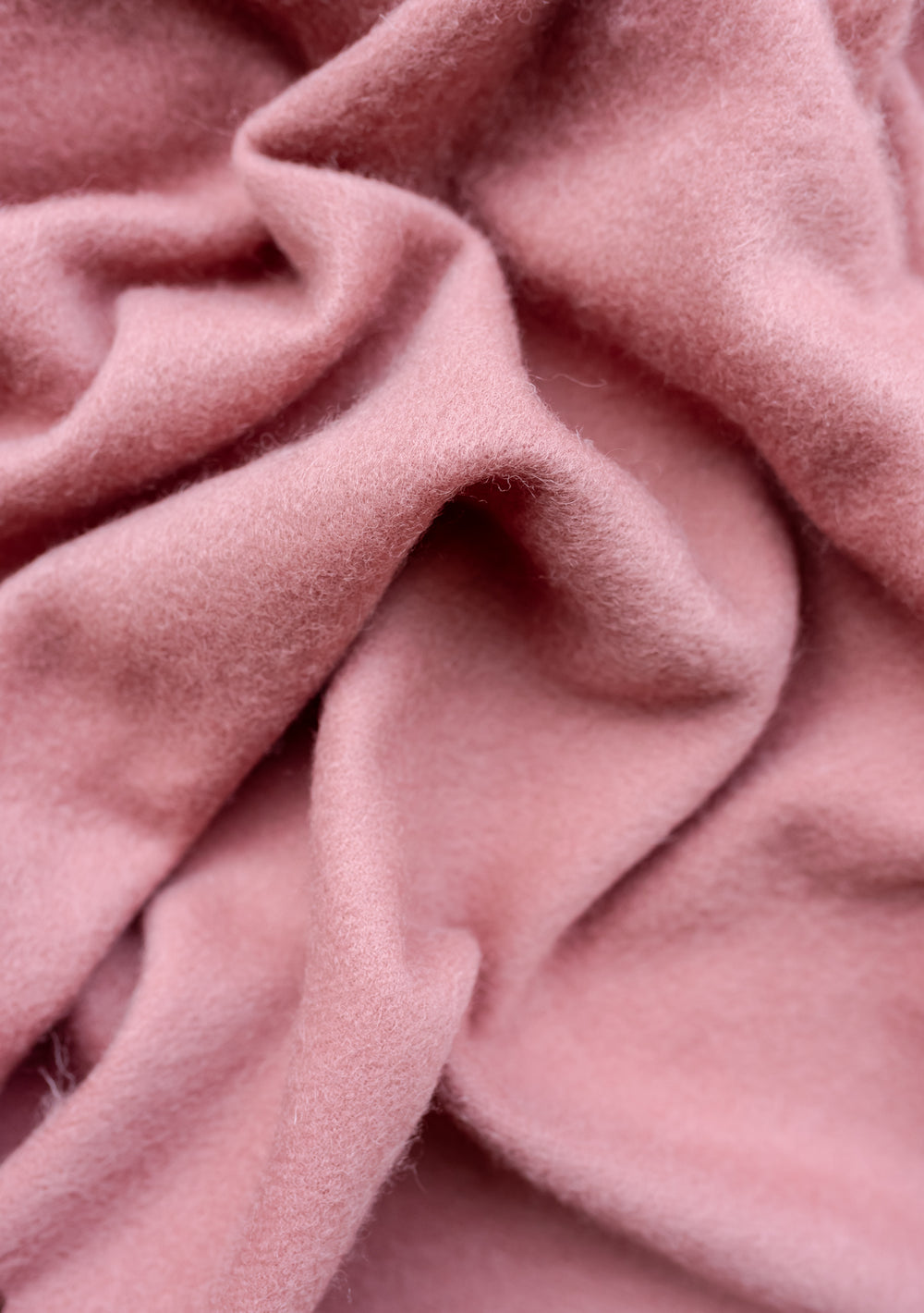 Close-up texture of TBCo Lambswool Baby Blanket in Blush showing soft, folded wool fabric with gentle ripples and creases