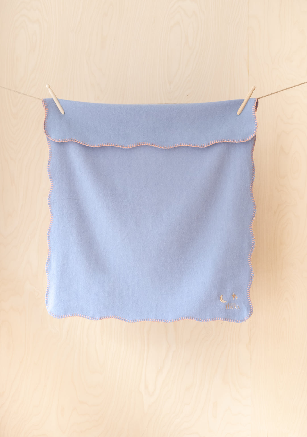 TBCo Lambswool Baby Blanket in lilac with peach scalloped edges and moon star embroidery hanging on clothesline