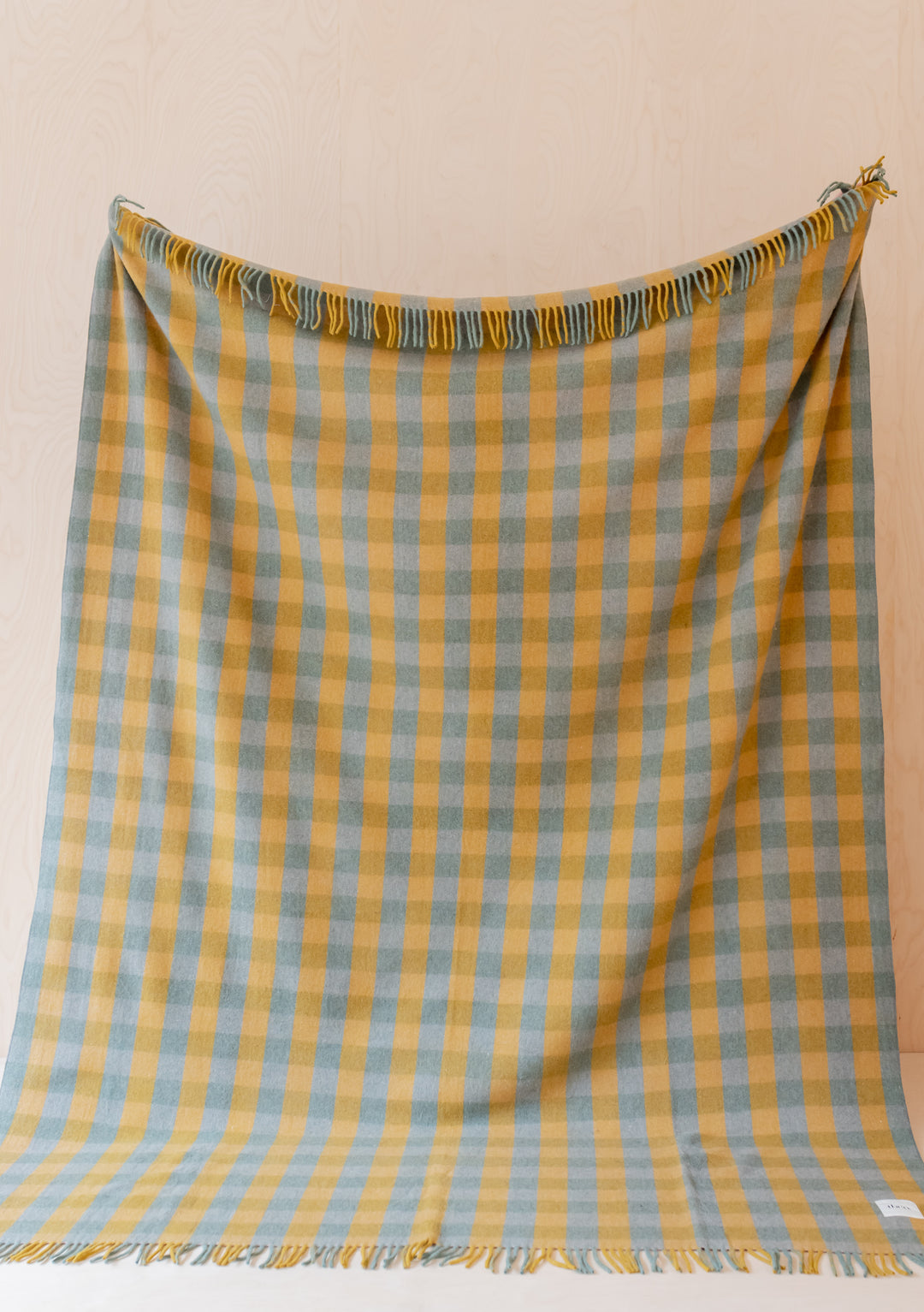 TBCo Recycled Wool Extra Large Blanket in sage and yellow gingham pattern with fringed edges displayed hanging