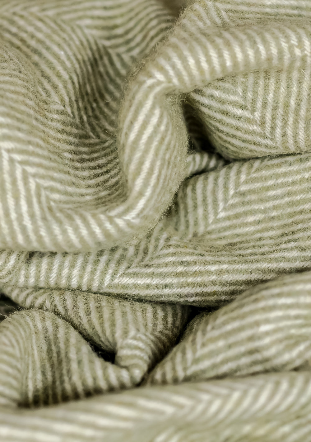 Close-up detail of TBCo Recycled Wool Kids Blanket in Olive Herringbone showing textured weave pattern and soft folds