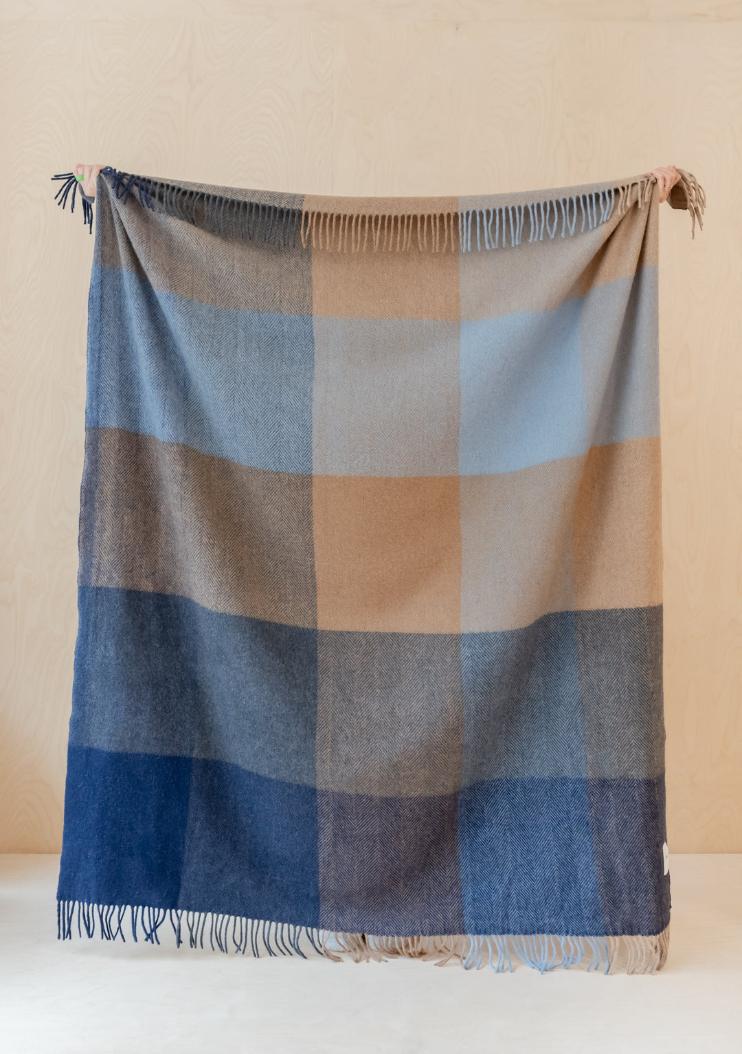 TBCo Recycled Wool Blanket in blue herringbone block check pattern displayed with fringe detail against neutral wall