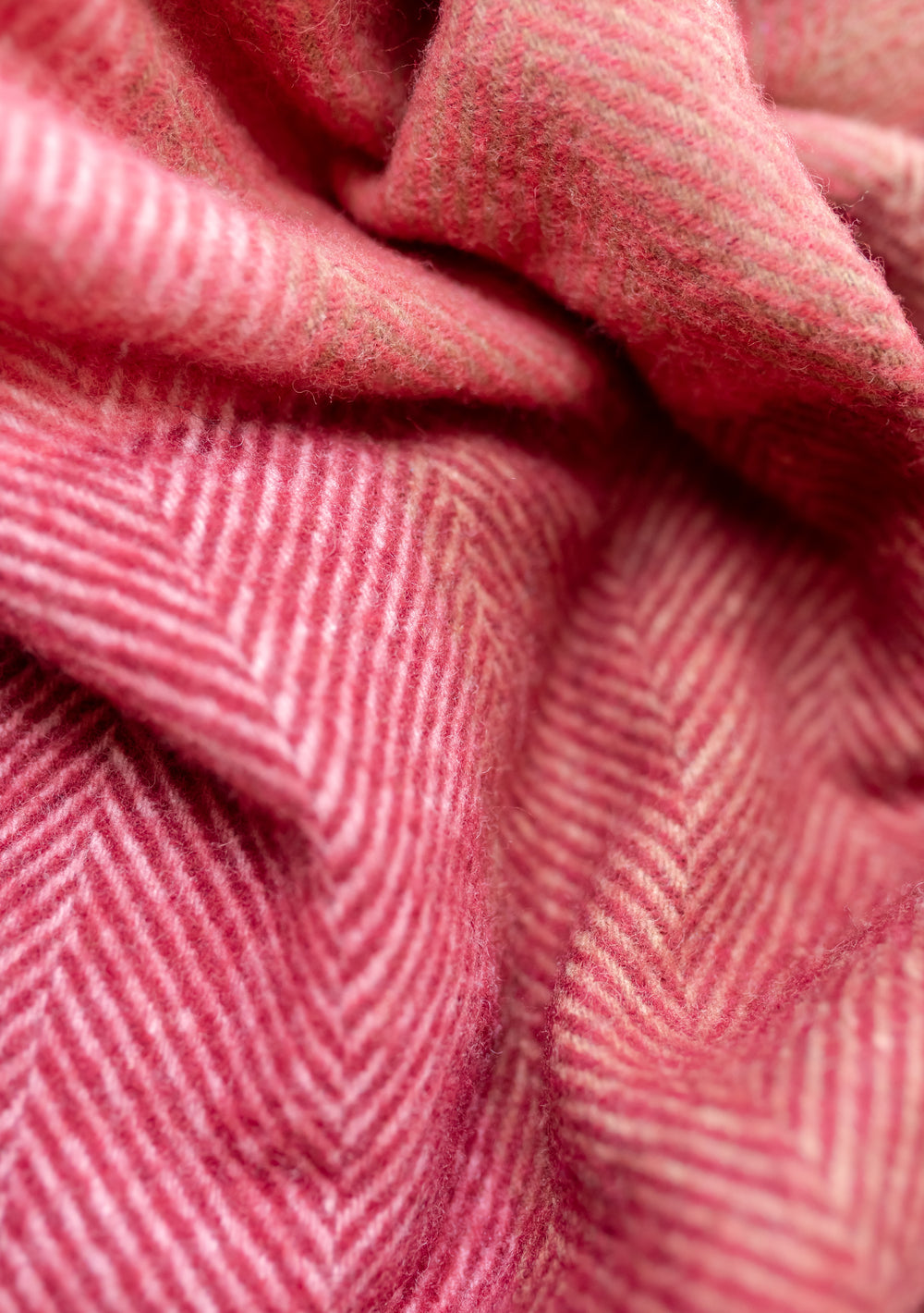 Close-up detail of TBCo recycled wool blanket in pink herringbone block check pattern showing textured weave