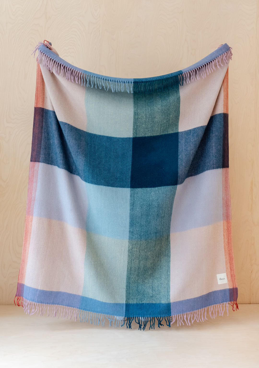 TBCo Recycled Wool Blanket in Apricot Frame Check displayed with fringed edges, featuring pink, blue and teal block pattern design