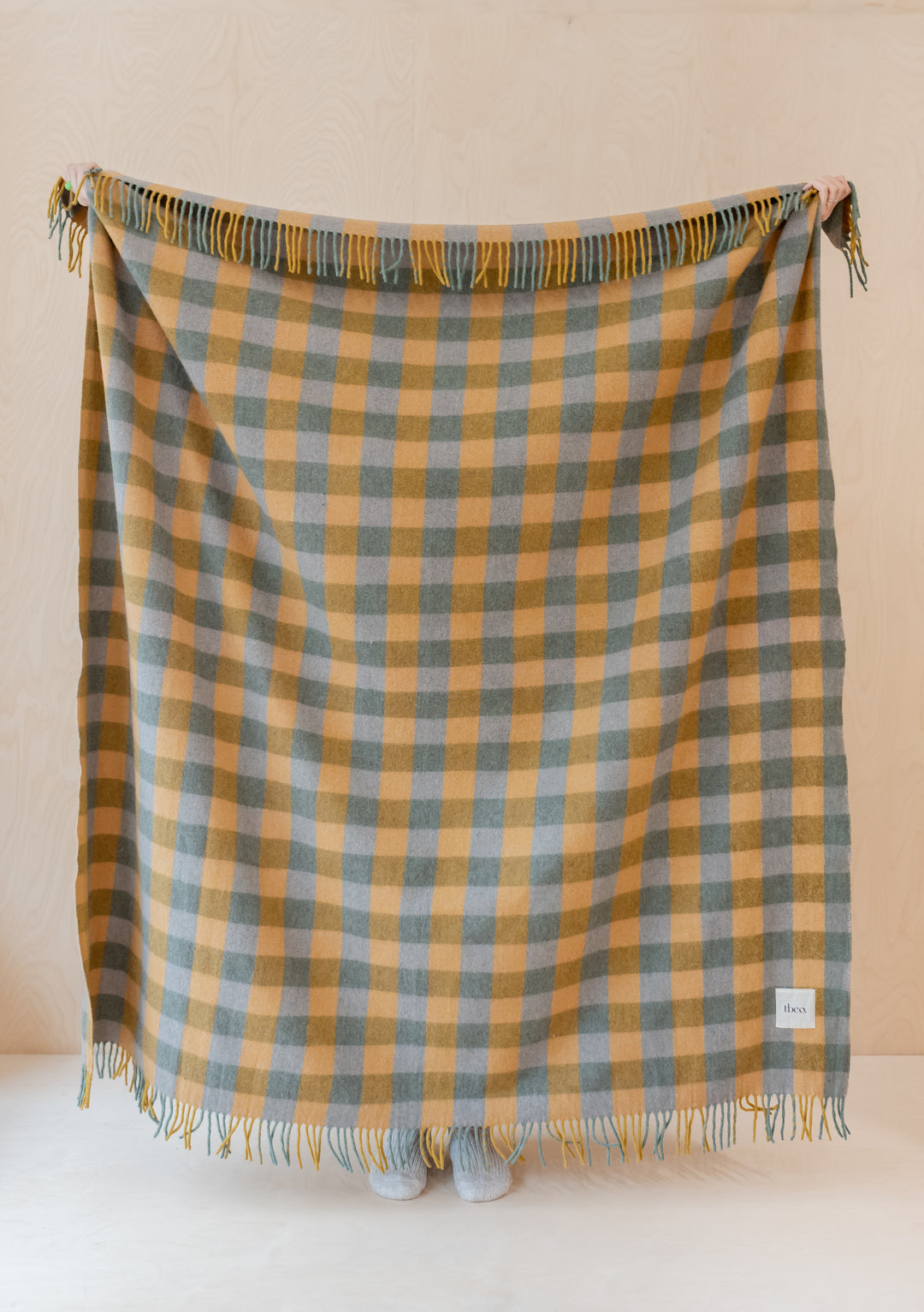 TBCo Recycled Wool Blanket in sage gingham pattern with mustard checks and fringed edges, displayed against cream wall