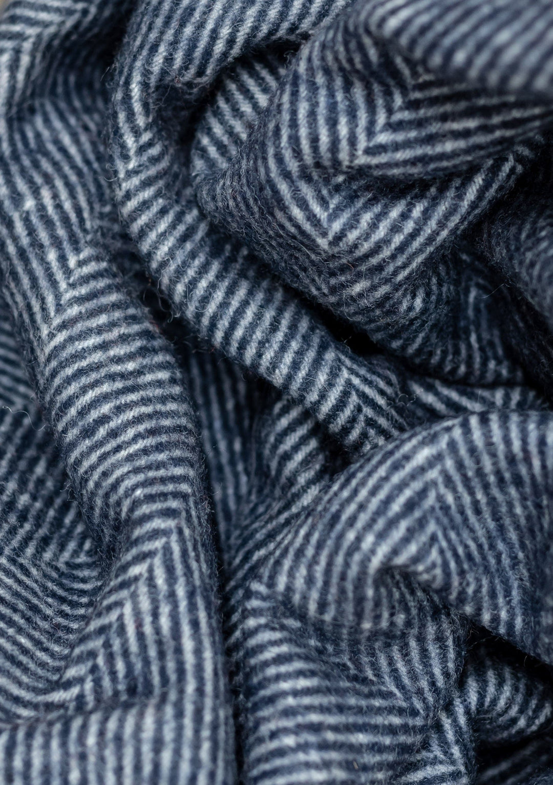 Close-up texture detail of TBCo Recycled Wool Small Blanket in Navy Herringbone pattern showing woven wool fibres