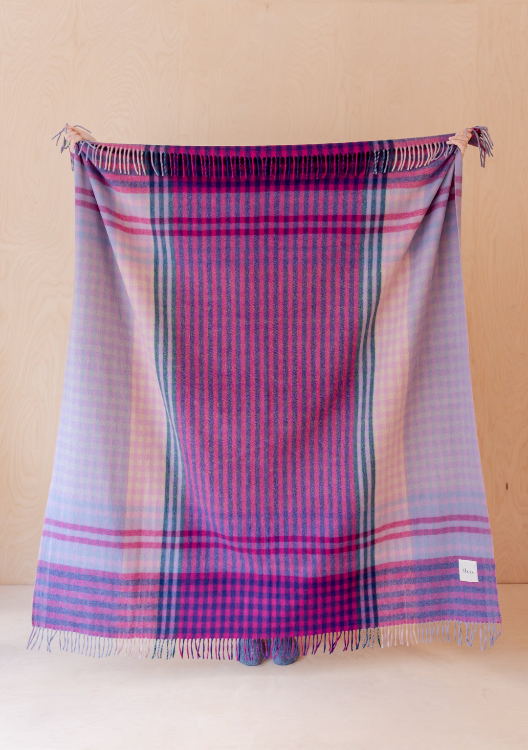 TBCo Recycled Wool Blanket in Lavender Micro Gingham featuring multicoloured stripes and fringe detail on wooden background