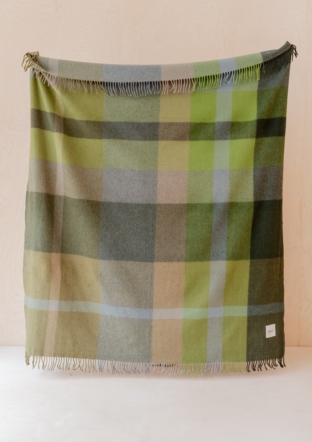 TBCo Recycled Wool Blanket featuring olive green patchwork check pattern with fringed edges displayed against neutral wall