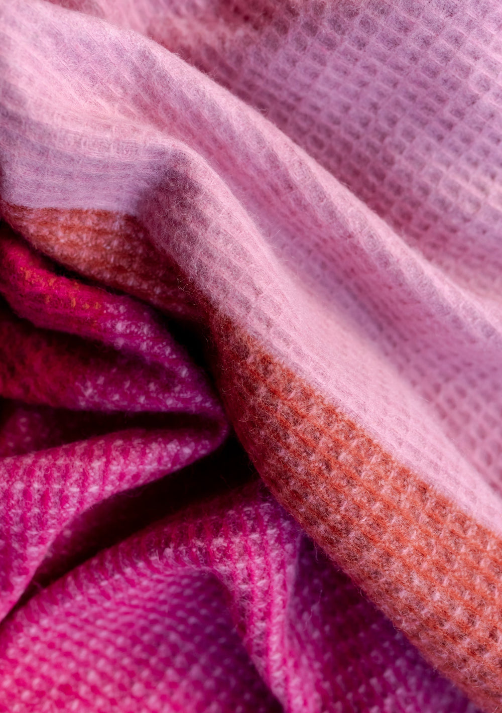 Close-up texture detail of TBCo Recycled Wool Blanket in Pink Waffle Block showing pink, rust and magenta waffle weave pattern