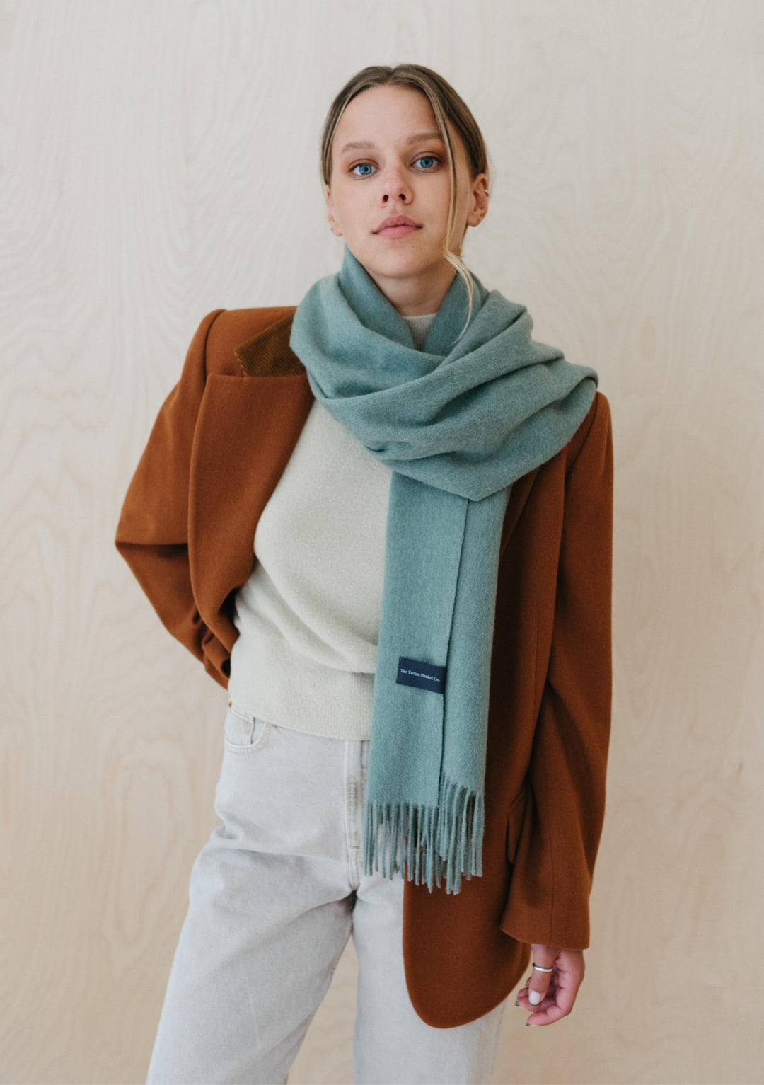 A model wearing TBCo Lambswool Oversized Scarf in Sage Melange styled with brown blazer and light-coloured casual outfit