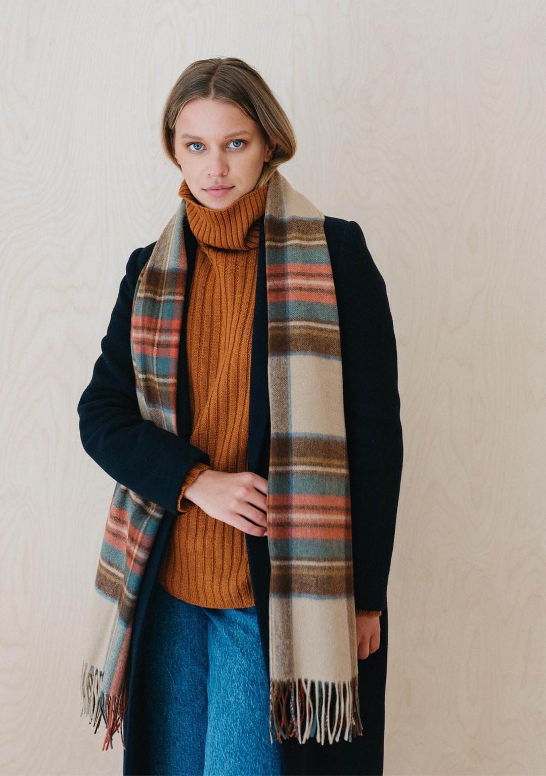 TBCo Stewart Dress Antique Tartan lambswool scarf styled with black coat and orange turtleneck, showing plaid pattern and fringe