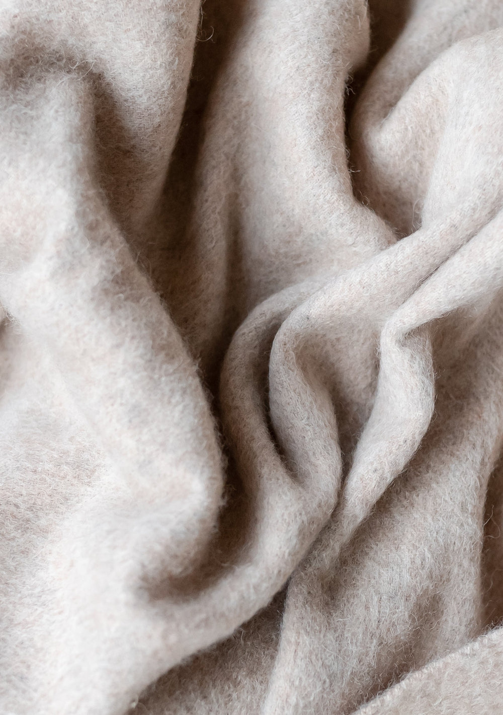 Close-up texture of TBCo Lambswool Small Blanket in Oatmeal Melange showing soft, wavy wool fibres with natural cream colour