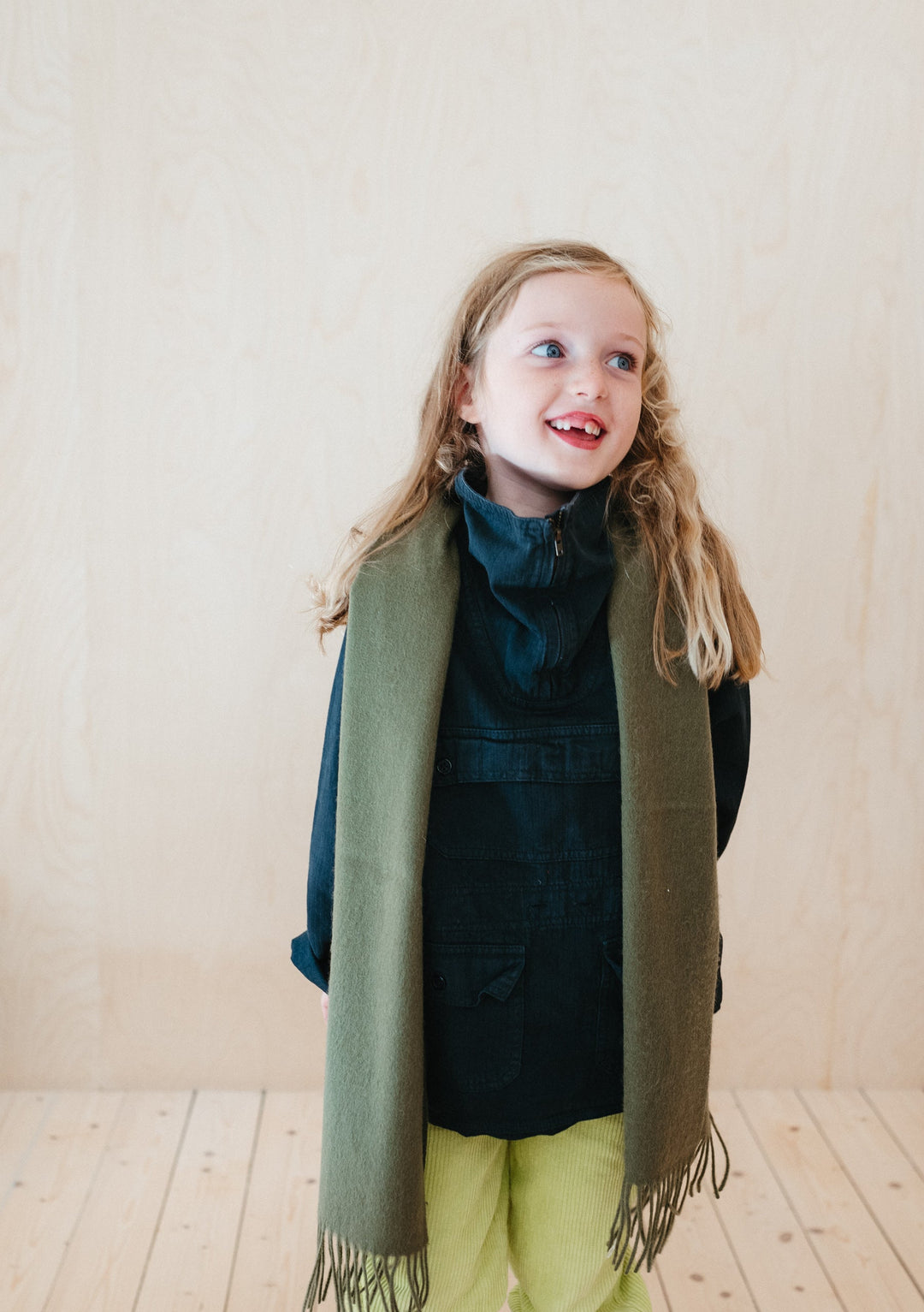 TBCo Kids Lambswool Scarf in Olive draped stylishly over navy winter outfit, showcasing soft texture and fringed edges