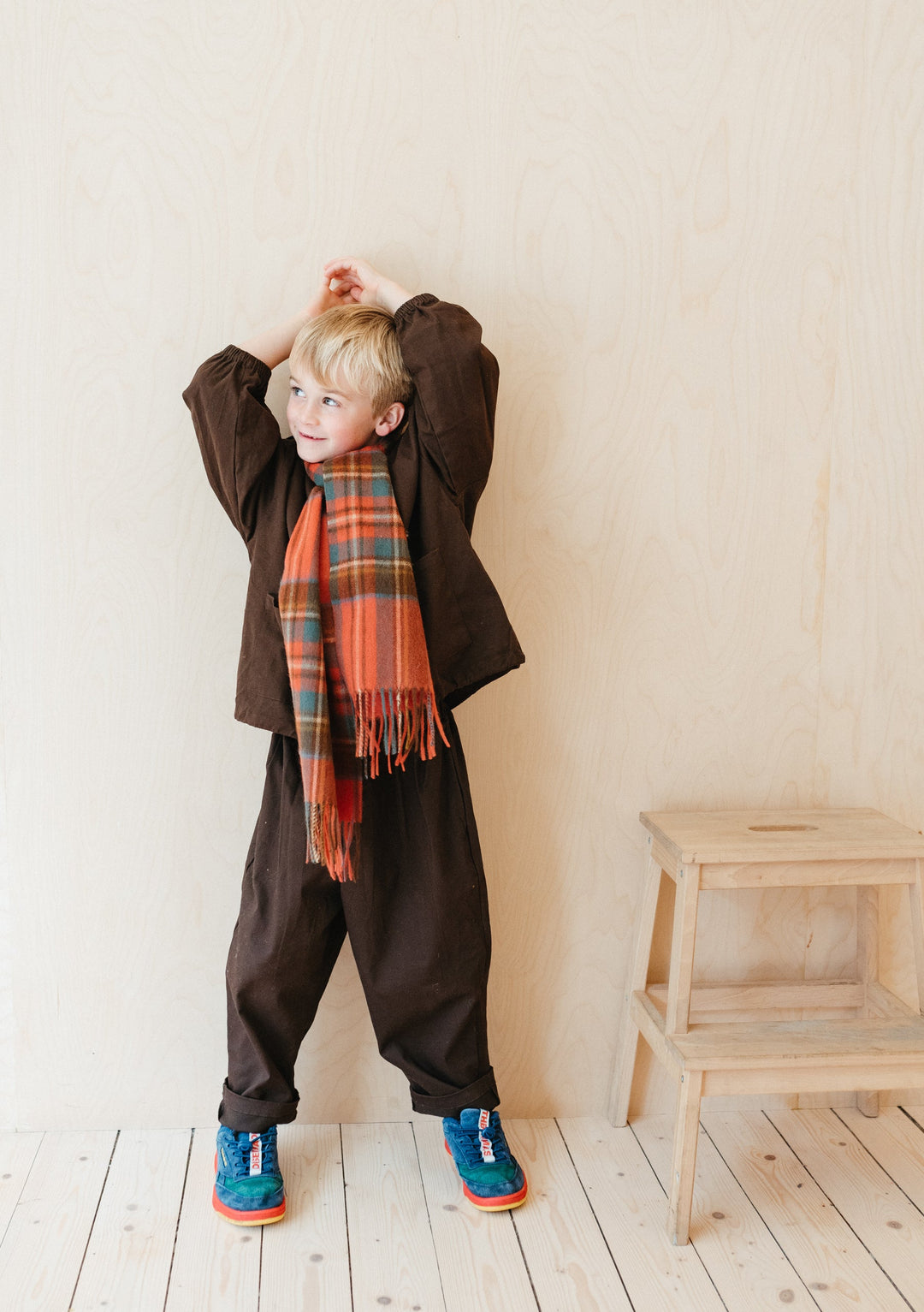 Child wearing TBCo Lambswool Kids Scarf in Stewart Royal Antique Tartan with brown outfit and blue trainers