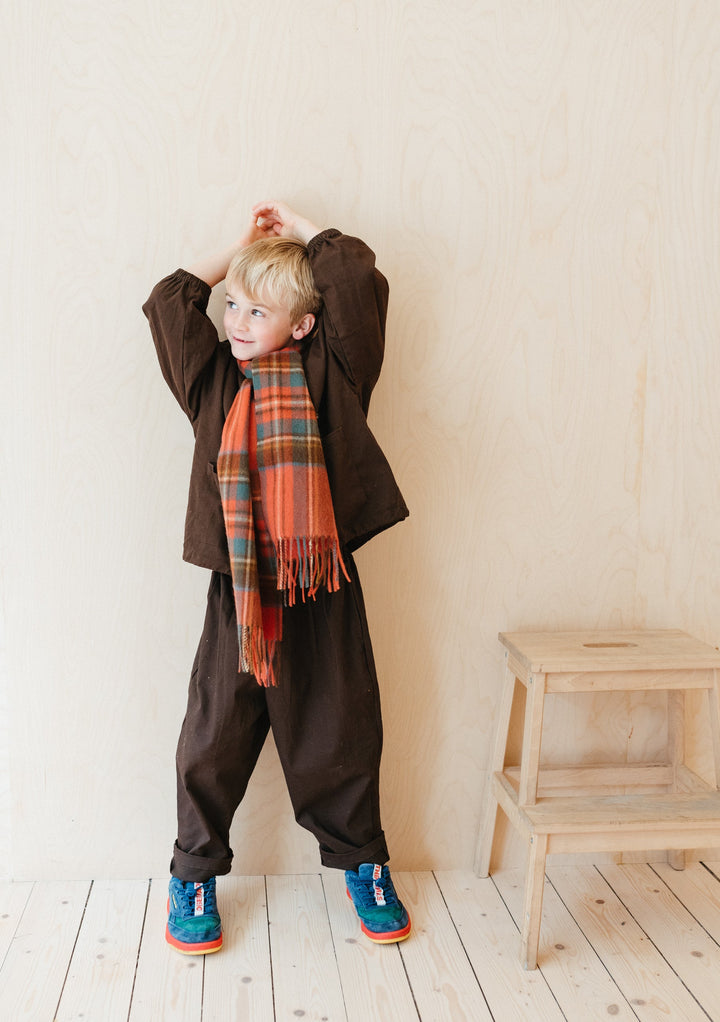 Child wearing TBCo Lambswool Kids Scarf in Stewart Royal Antique Tartan with brown outfit and blue trainers