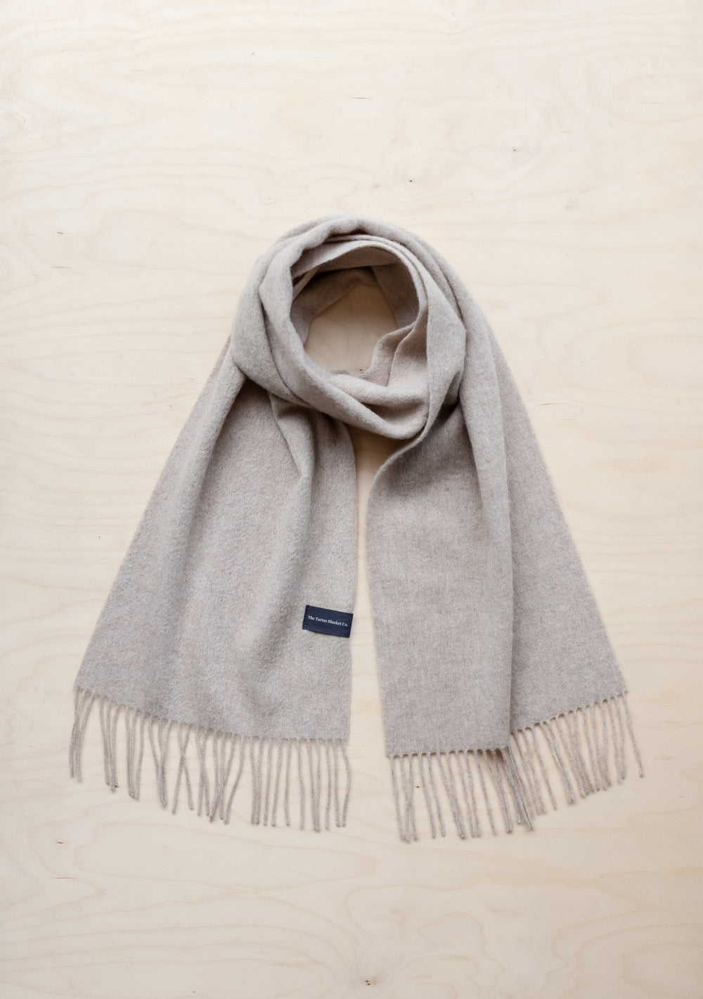 TBCo Lambswool Scarf in Oatmeal Melange with fringed ends, displayed flat against cream background, showing soft texture