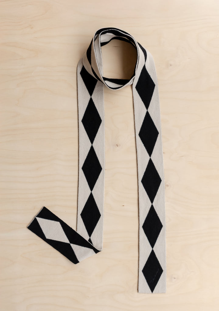 TBCo Merino Wool Skinny Scarf in Black Harlequin on a wooden background.