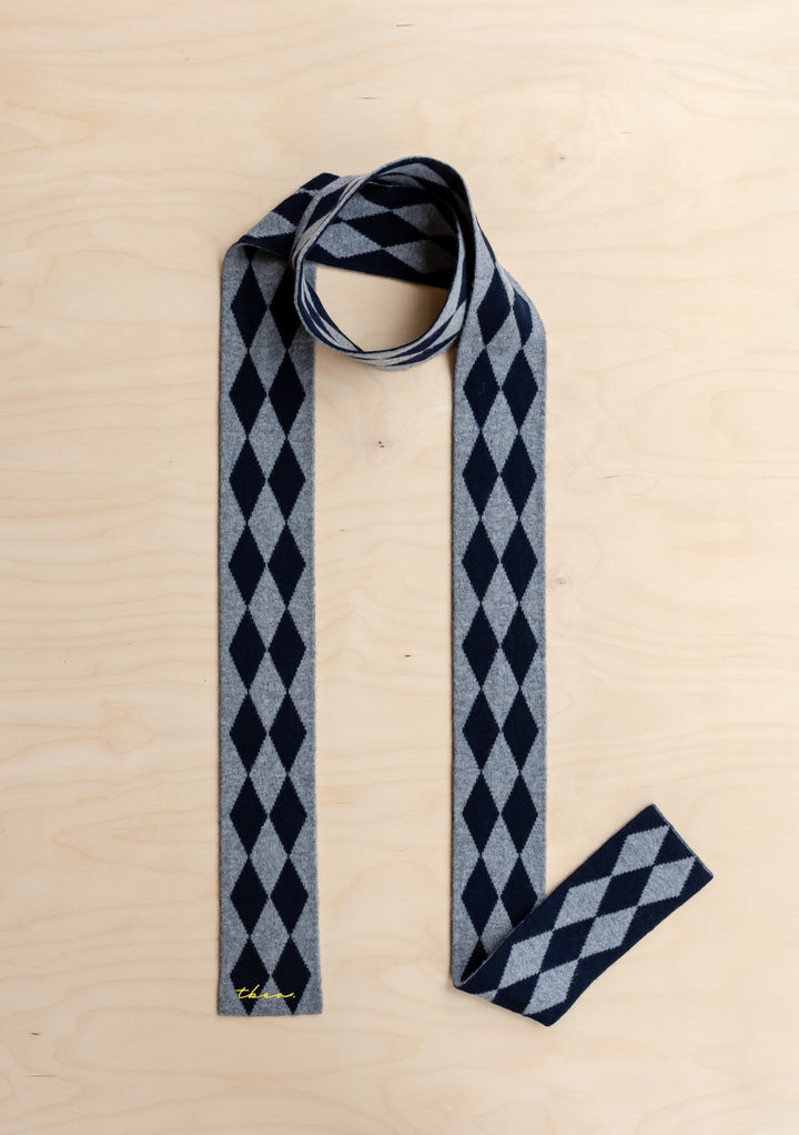 TBCo Merino Wool Skinny Scarf in Charcoal Harlequin, on a wooden background