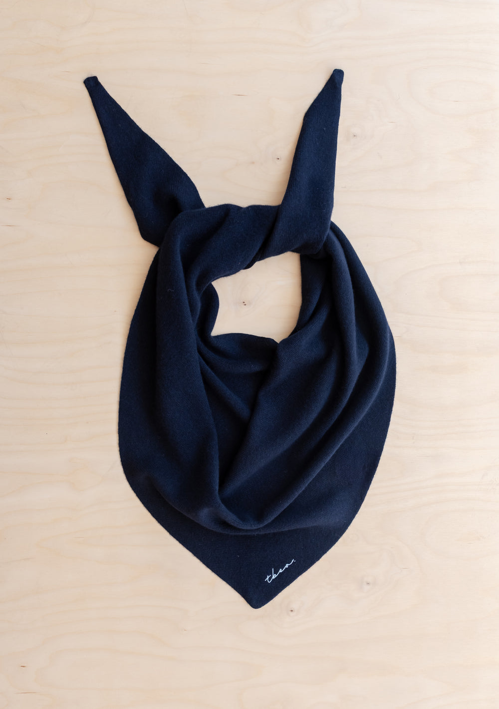 TBCo Navy-blue merino wool triangle scarf, laid flat with tied corners, features an embroidered TBCo logo.