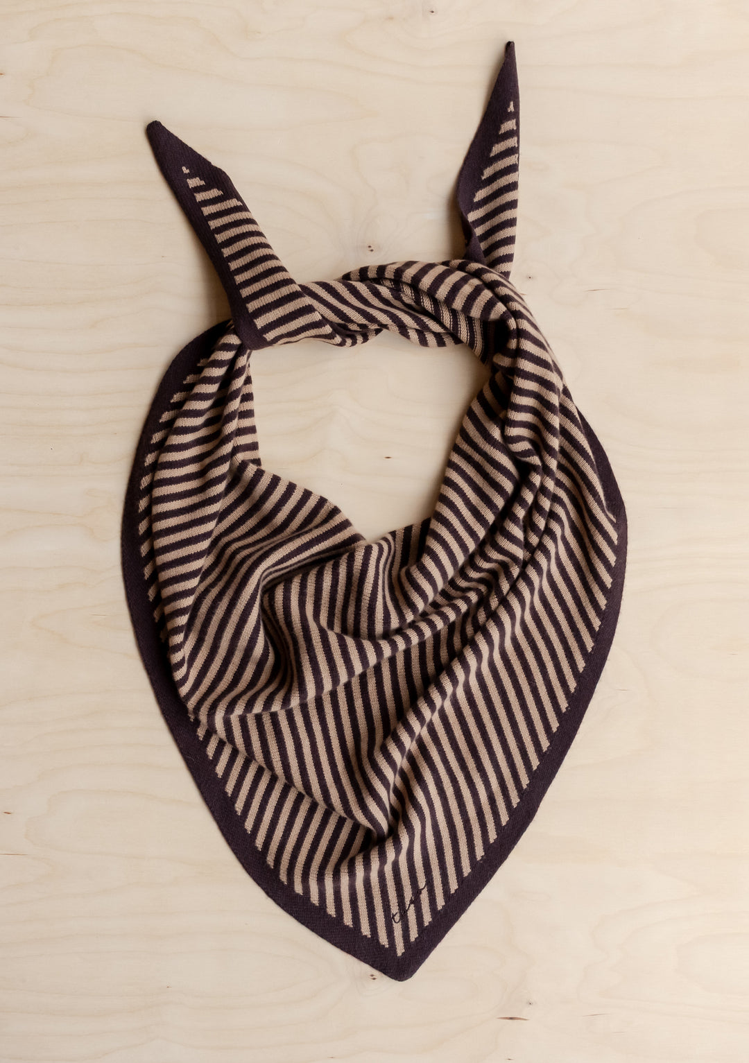 TBCo Large Merino Wool Triangle Scarf in Camel & Brown Stripe, featuring a knit design with narrow stripes, laid flat on wood, with corners tied in a knot.