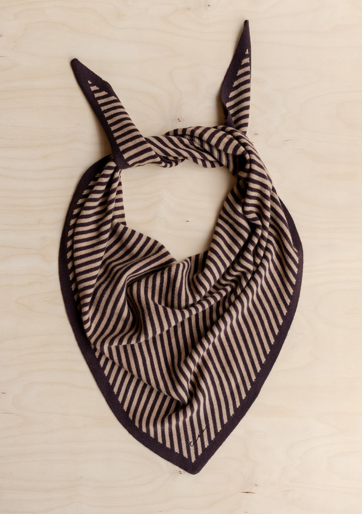 TBCo Large Merino Wool Triangle Scarf in Camel & Brown Stripe, featuring a knit design with narrow stripes, laid flat on wood, with corners tied in a knot.