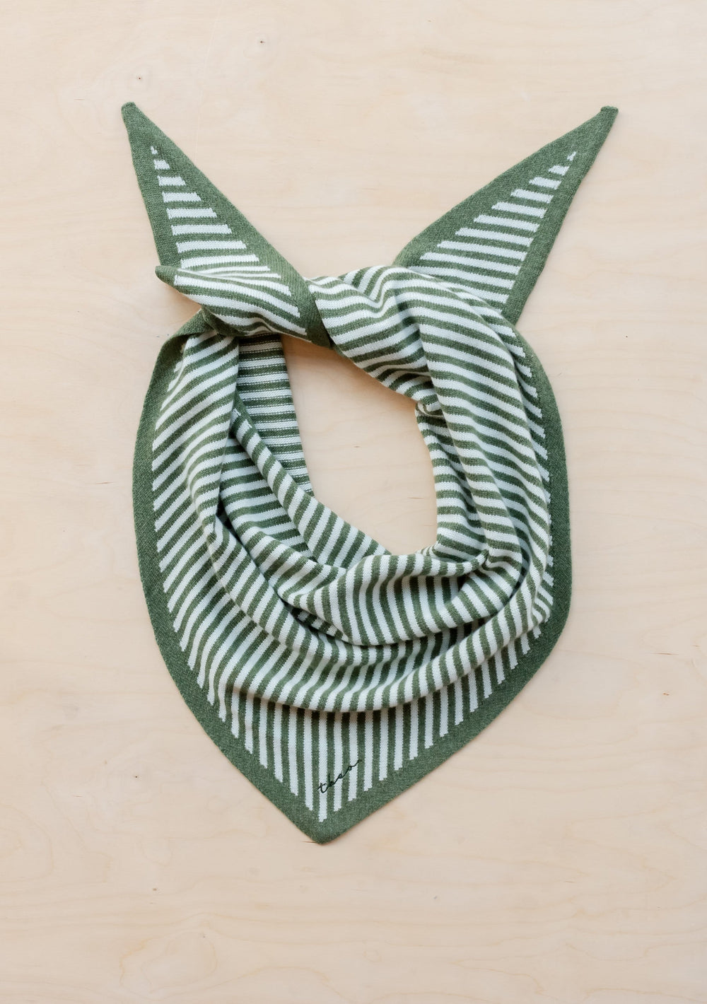 TBCo Large Merino Triangle Scarf in green and white stripes, styled in a classic bandana fold on beige background