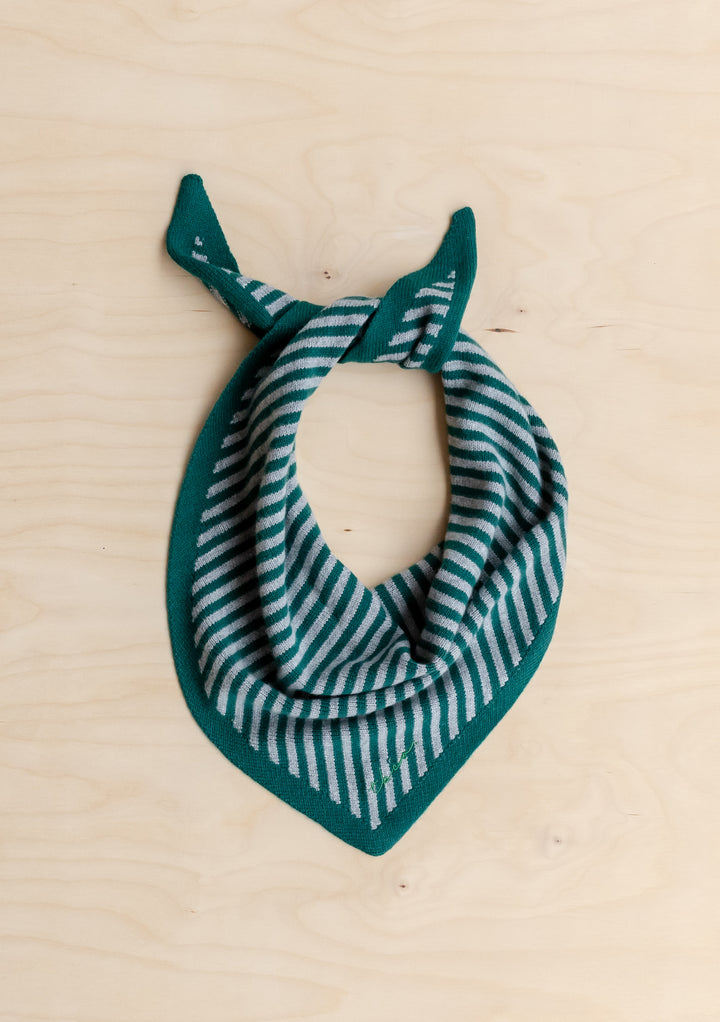 TBCo Merino Wool Triangle Scarf in Green & Charcoal Stripe, showcasing a forest green knit with light-gray stripes, laid flat on a light wood surface.