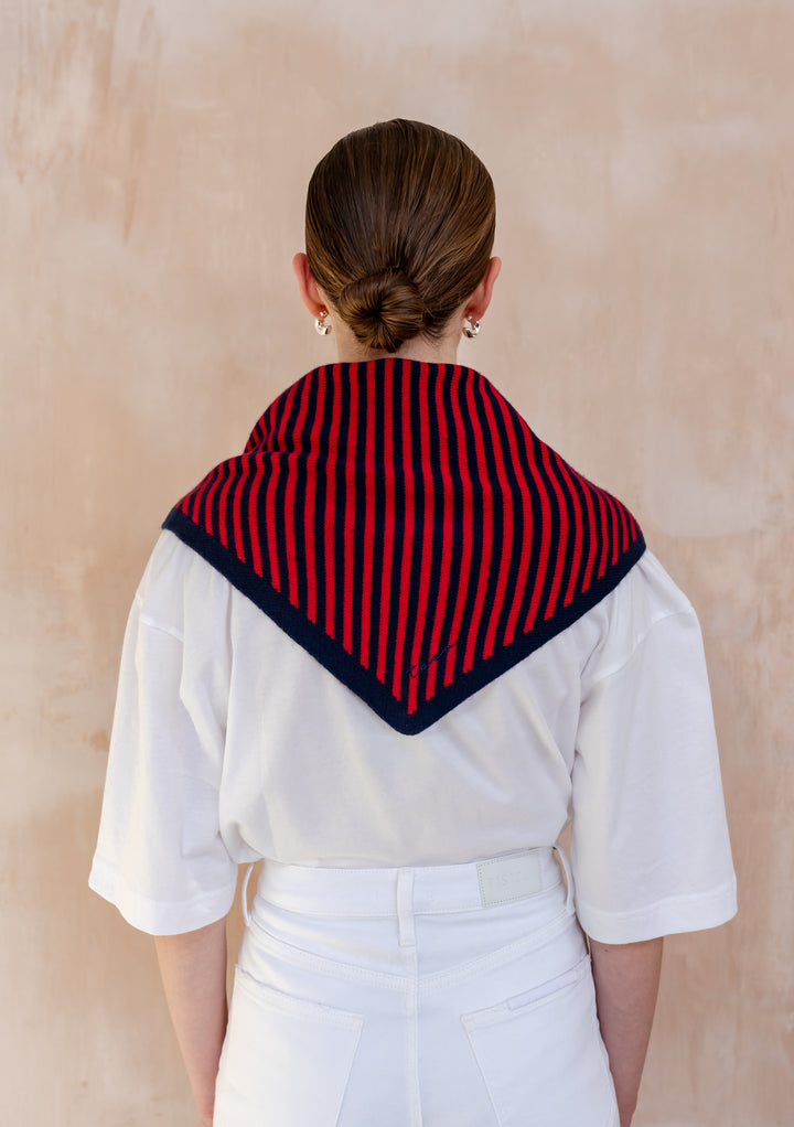Person wearing TBCo Merino Wool Triangle Scarf in Navy & Red Stripe, featuring red and navy vertical stripes, over a white T-shirt and high-waisted jeans.