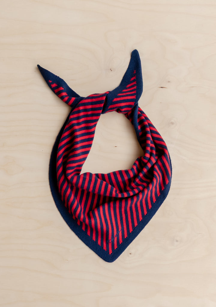 TBCo Merino Wool Triangle Scarf in Navy & Red Stripe, woven in soft merino wool with a TBCo logo, laid on a light wood surface.