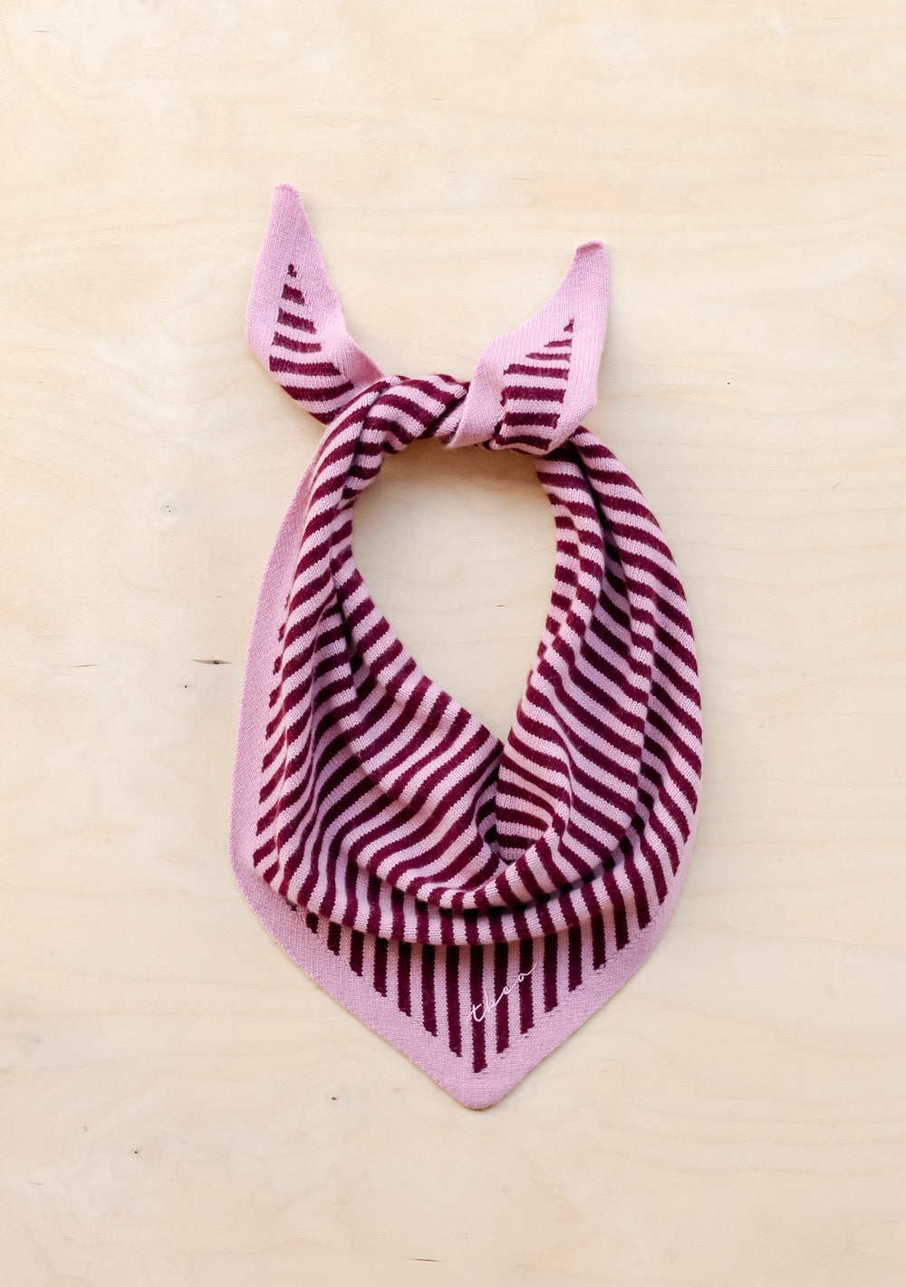 TBCo Merino Triangle Scarf in pink and burgundy stripes, tied in bandana style against cream background, showing soft wool texture