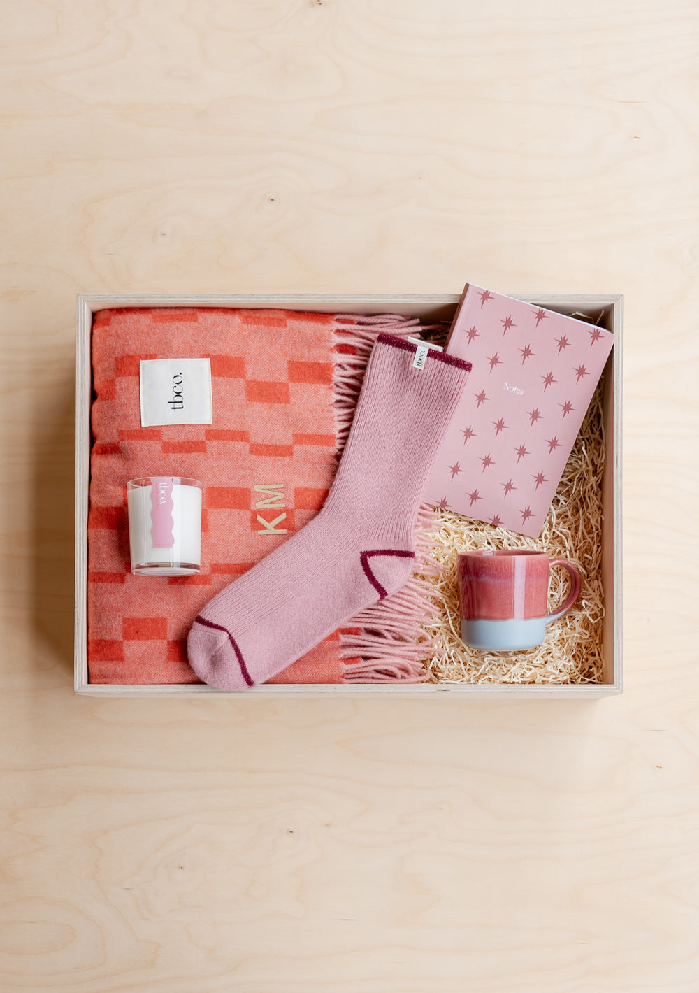 TBCo Build Your Own Mothers Day Gift Box featuring cozy pink socks, coral blanket, candle and ceramic mug nestled in straw