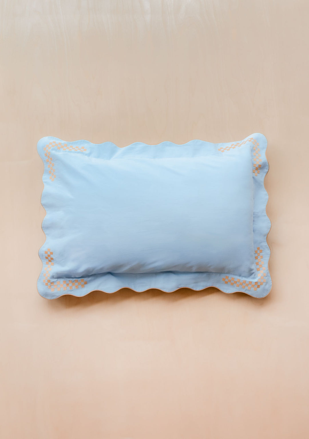 TBCo Cotton & Linen Pillowcase with blue scalloped edges and camel checkerboard embroidery on a beige background