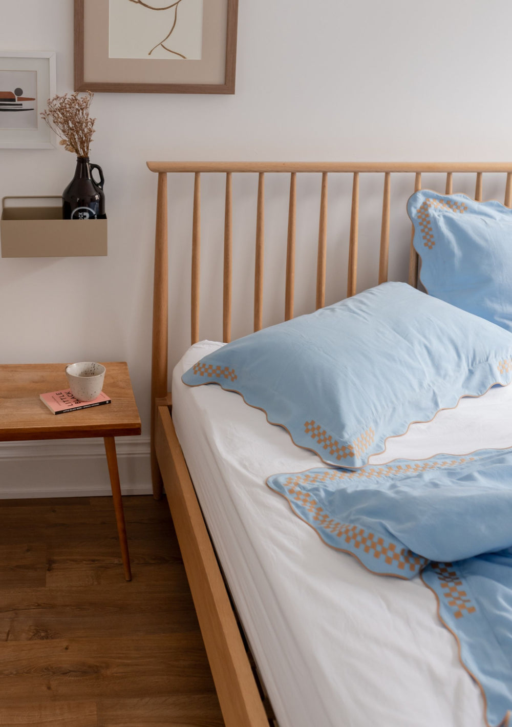 TBCo Cotton & Linen Pillowcases in blue with scalloped edges and checkerboard embroidery on wooden bed frame