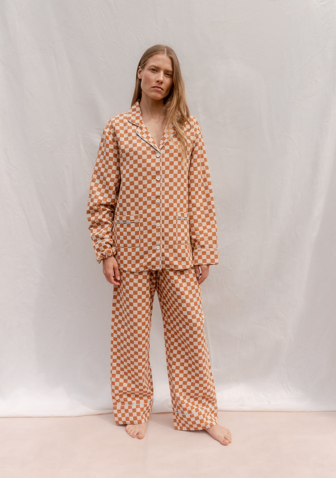 Woman wearing TBCo Cotton Pyjamas in Honey Checkerboard featuring breathable cotton and classic honey yellow pattern.