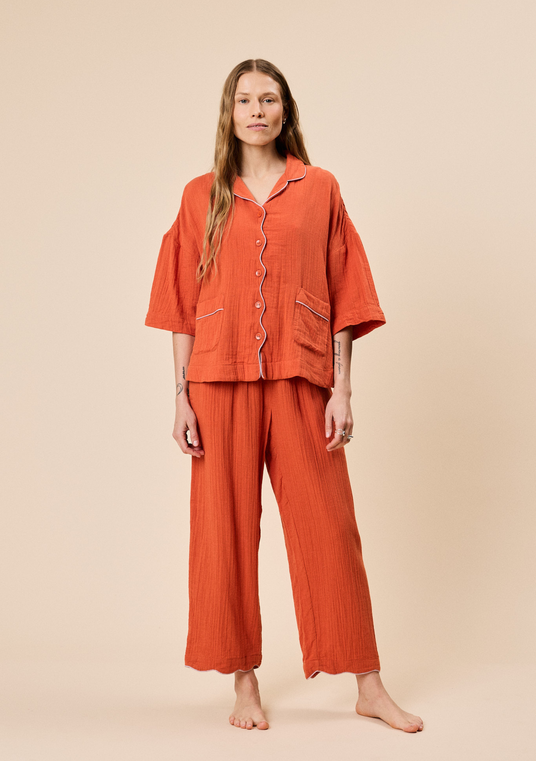 Woman wearing relaxed fit TBCo Cotton Pyjamas in Rust with button front and contrast piped trim details