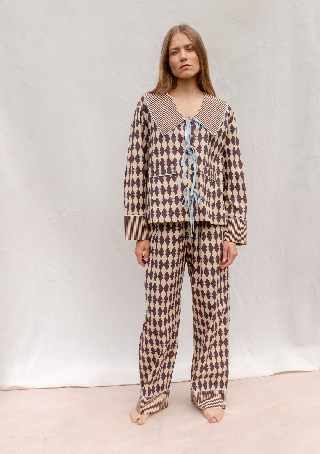 Cotton Pyjamas in Camel Harlequin by TBCo featuring breathable cotton, harlequin pattern, blue bows, and striped collar and cuffs.