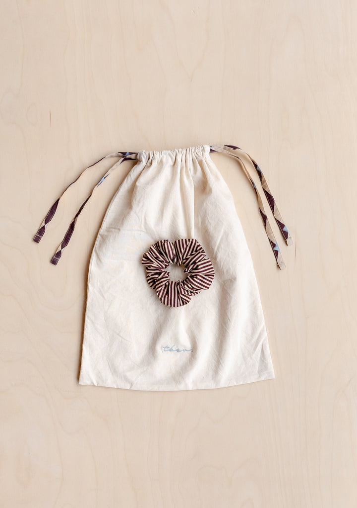 Cotton Pyjamas in Camel Harlequin by TBCo storage bag and matching striped scrunchie on wooden background.