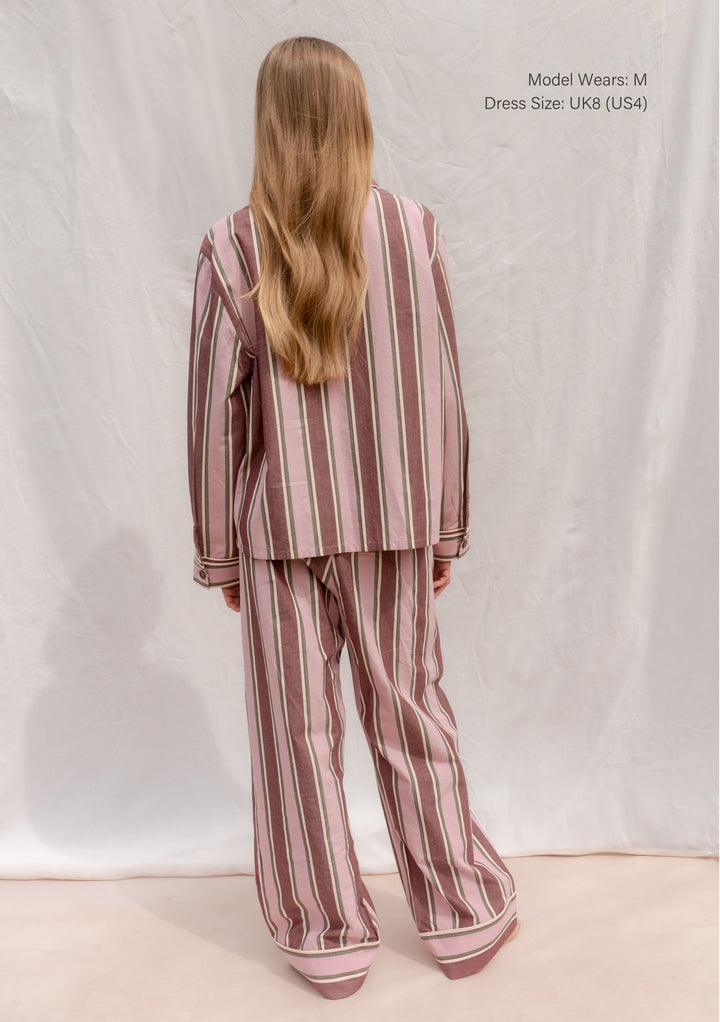 Back view of TBCo Cotton Pyjamas in Pink Stripe worn by model with long hair in a relaxed pose.