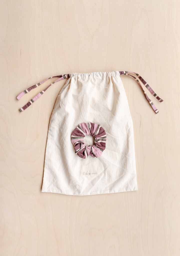 Cotton Pyjamas in Pink Stripe by TBCo drawstring bag with matching pink striped scrunchie on wooden surface