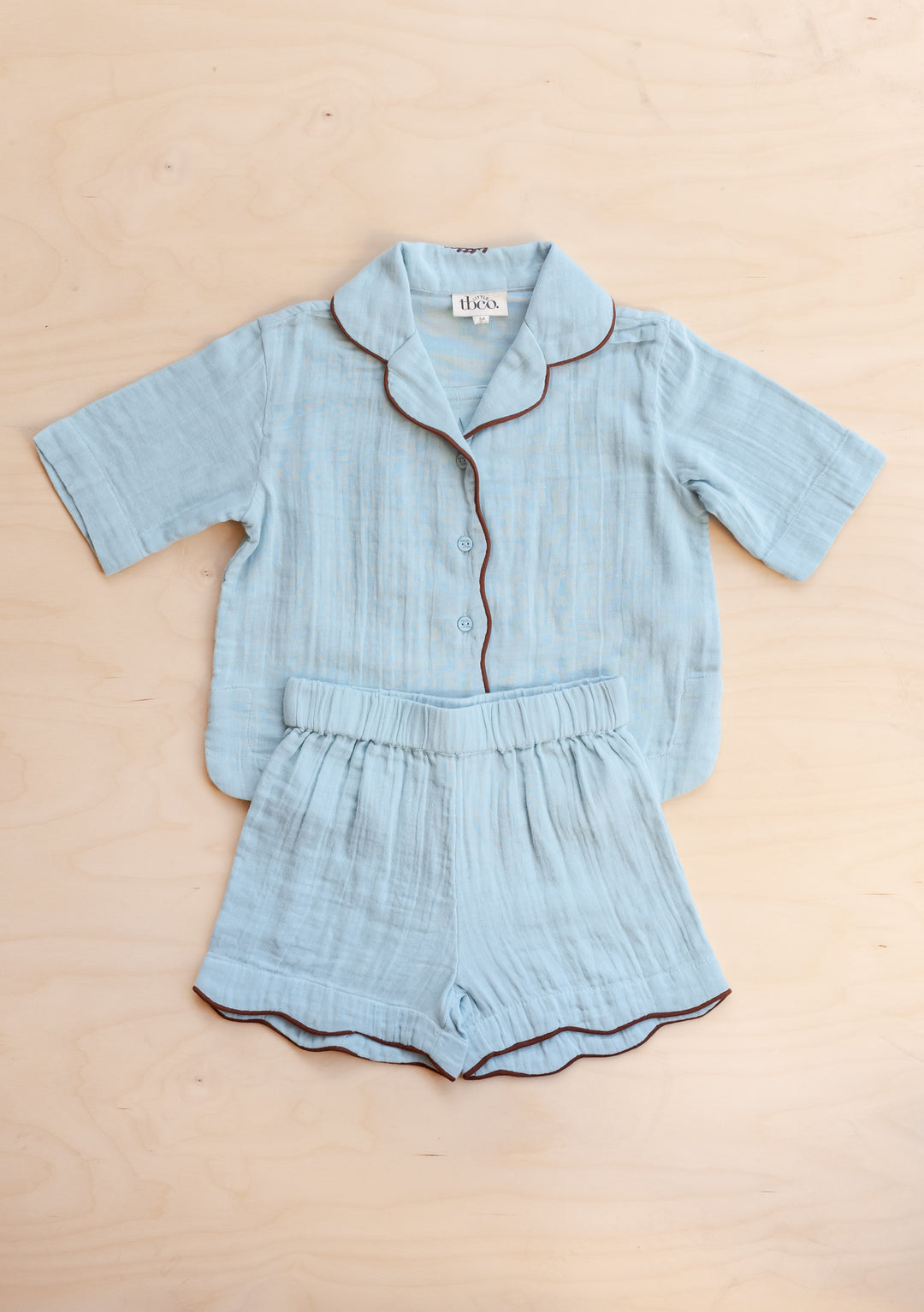 TBCo Cotton Kids Pyjamas in Blue with short sleeves, scalloped trim, and elasticated shorts on neutral backdrop