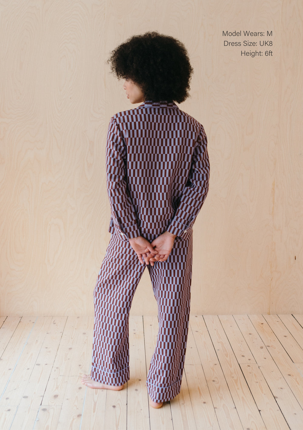 Back view of TBCo Cotton Pyjamas in Lilac Checkerboard pattern, showing oversized fit and full-length design on wooden floor